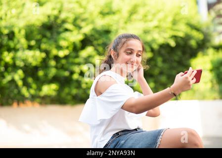 Ragazza felice adolescente che prende una foto selfie all'aperto Foto Stock