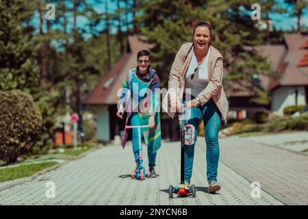 Due donne che si divertono nel parco mentre cavalcano uno scooter Foto Stock