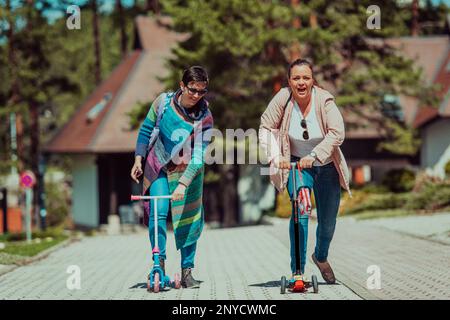 Due donne che si divertono nel parco mentre cavalcano uno scooter Foto Stock