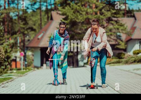 Due donne che si divertono nel parco mentre cavalcano uno scooter Foto Stock