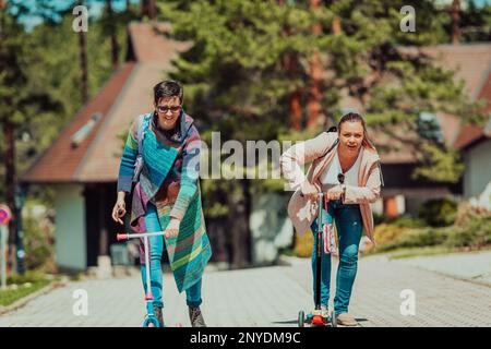 Due donne che si divertono nel parco mentre cavalcano uno scooter Foto Stock