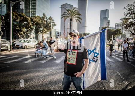 Tel Aviv, Israele. 01st Mar, 2023. Un manifestante detiene la bandiera israeliana mentre blocca la strada durante una manifestazione a Tel Aviv. Mercoledì, la polizia israeliana ha sparato granate e scuffi a Tel Aviv e a Gerusalemme durante un 'disfacimento' a livello nazionale, aumentando l'intensità delle proteste contro un piano governativo per la revisione della magistratura. Credit: SOPA Images Limited/Alamy Live News Foto Stock