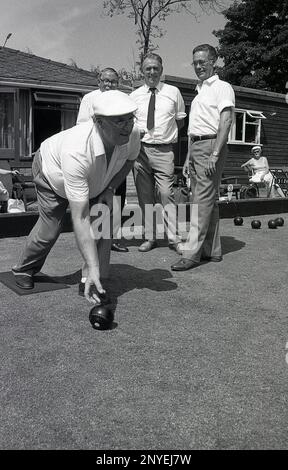 1989, storico, bowling su prato, all'esterno di un circolo, tre uomini guardano un altro uomo che lancia una palla su un campo da bowling, Inghilterra, Regno Unito. Foto Stock