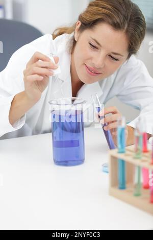 scienziato femminile che utilizza la pipetta in laboratorio Foto Stock