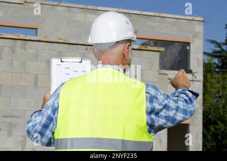 vista posteriore dell'allestitore senior in loco che fornisce istruzioni Foto Stock