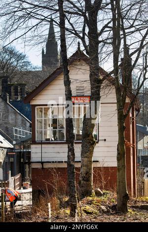 La segnaletica della stazione di Alston sulla South Tynedale a scartamento ridotto Heritage Railway con la chiesa di Alston sullo sfondo in una giornata di sole ad Alston Cumbria Foto Stock