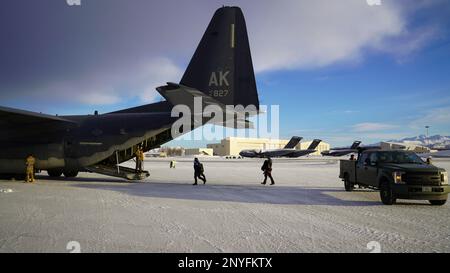 Parasalvemen dal 212th Rescue Squadron carica l'ingranaggio su un RQS HC-130J Combat King II 211th alla base congiunta Elmendorf-Richardson, Alaska, 7 febbraio 2023. L'HC-130J e il personale di soccorso, insieme all'elicottero 210th RQS HH-60G a nave Hawk, siedono in guardia per la missione federale di ricerca e salvataggio nella vasta regione artica dell'Alaska. La capacità di rifornimento aereo del modello HC-130Diplotante estende in modo significativo la gamma di nave Hawk HH-60G per lo svolgimento di missioni di ricerca e recupero. Foto Stock