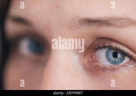Primo piano di occhi azzurri femminili sfrecciati che guardano la telecamera a fuoco morbido con ciglia lunghe Foto Stock