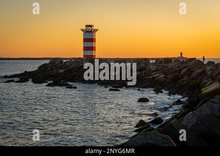 Faro al molo nord Ijmuiden al tramonto con una vista sul molo sud in lontananza Foto Stock