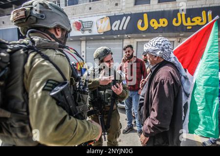 Nablus, Palestina. 02nd Mar, 2023. Un anziano palestinese si oppone ai soldati israeliani mentre alza la bandiera palestinese durante una protesta contro gli attacchi dei coloni ebrei e la chiusura dei negozi commerciali da parte dell'esercito israeliano nella città di Hawara, a sud di Nablus, nella Cisgiordania occupata. Credit: SOPA Images Limited/Alamy Live News Foto Stock