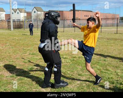 PORTSMOUTH, Virginia (20 gennaio 2023) il compagno di Boatswain Seaman Kevin Calderon usa un calcio per scoraggiare l'assalente "uomo rosso" dopo essere stato spruzzato con lo spruzzo di capsicum di oleoresina (OC) durante l'addestramento di base della forza di reazione di sicurezza (SRF-B) al cantiere navale di Portsmouth. SRF-B è un corso completo di due settimane che fornisce conoscenze di base per i marinai per svolgere il ruolo di sentry. Foto Stock