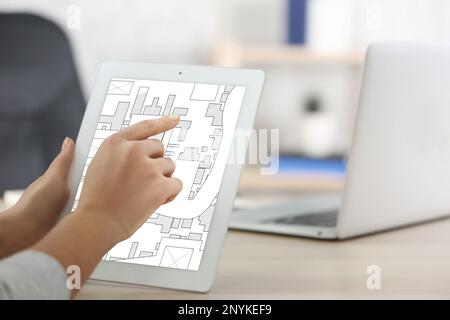 Donna che analizza mappa catastale su tablet alla scrivania, primo piano Foto Stock