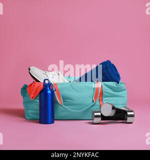 Borsa da palestra blu e accessori sportivi su sfondo rosa Foto Stock