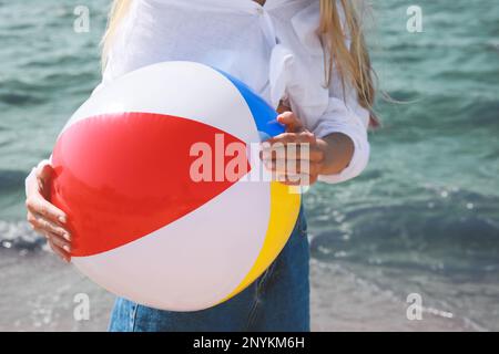 Giovane donna con pallina da spiaggia gonfiabile vicino al mare nelle giornate di sole, primo piano Foto Stock