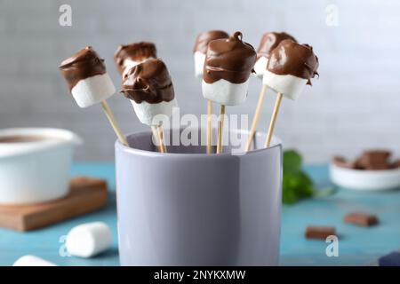 Deliziosi marshmallows ricoperti di cioccolato in tazza, primo piano Foto Stock