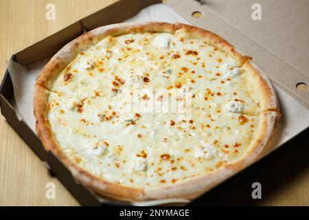 Quattro pizza al formaggio consegnata in una scatola. Delizioso piatto italiano quattro formaggi al forno con mozzarella, gorgonzolla, parmigiano e formaggio azzurro Foto Stock