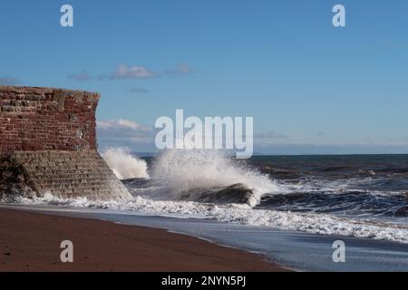 Onde che si infrangono contro la parete del mare a marea alta. Foto Stock