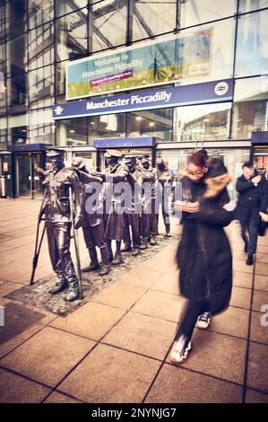 I pendolari del treno corrono davanti alla statua "Vittoria sulla cecità" fuori dalla stazione ferroviaria di Piccadilly, Manchester Foto Stock