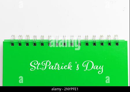 Quaderno verde con testo giorno San Patrizio su sfondo bianco. Concetto di celebrazione del giorno di San Patrizio Foto Stock