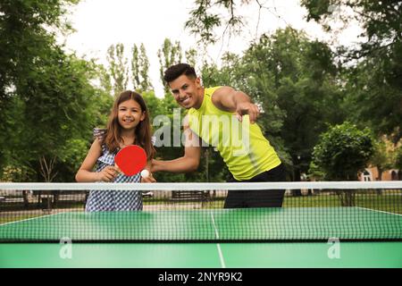 Felice uomo con sua figlia che gioca a ping pong nel parco Foto Stock