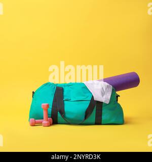 Borsa da palestra blu e accessori sportivi su sfondo giallo Foto Stock