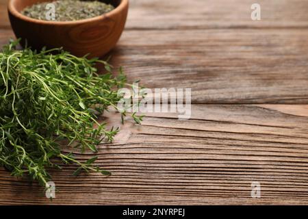 Ciotola con timo secco e erbe fresche su tavola di legno. Spazio per il testo Foto Stock