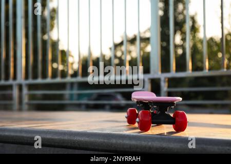 Moderno skateboard rosa con ruote rosse sulla rampa all'aperto. Spazio per il testo Foto Stock