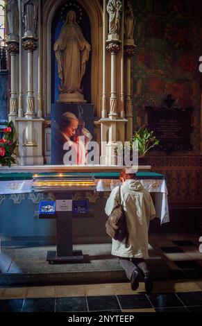 Donna orante davanti a Giovanni Paolo II ritratto , chiesa francescana, Cracovia in Polonia. Foto Stock