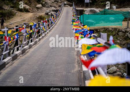 Sacre bandiere di preghiera multicolore poste su entrambi i lati del ponte che si muovono nel vento mostrando una preghiera bhuddist incantazione comune in collina Foto Stock