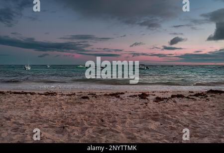 Barche da pesca galleggiano nelle acque turchesi del Mar dei Caraibi durante un bellissimo tramonto delle Barbados Foto Stock