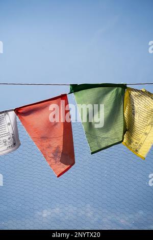 Bandiere di preghiera multicolore sacre sulla recinzione che si muovono nel vento mostrando un incantamento di preghiera bhuddist comune nelle stazioni collinari di Himachal Foto Stock