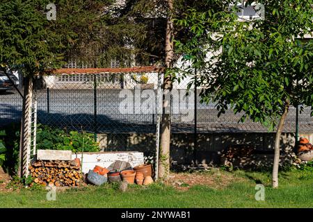 Vasi di fiori di ceramica e legna da ardere impilati nel cortile. Pentole di terracotta. Foto Stock