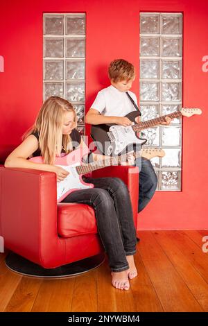 Vita di famiglia, duetto di chitarra. Un paio di giovani aspiranti musicisti che si concentrano sul suonare i loro strumenti. Da una serie di immagini correlate. Foto Stock