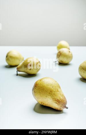 Qualche pere mature sulla superficie di un sottile e morbido colore blu Foto Stock