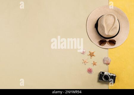 Telo da spiaggia, cappello, occhiali da sole, macchina fotografica, stelle marine e conchiglie sulla sabbia, giacitura piatta. Spazio per il testo Foto Stock