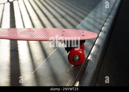 Moderno skateboard rosa con ruote rosse sulla rampa all'aperto, primo piano Foto Stock