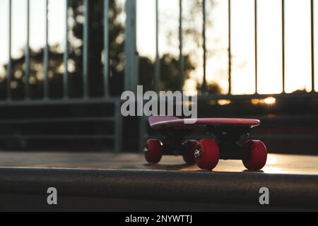 Moderno skateboard rosa con ruote rosse sulla rampa all'aperto. Spazio per il testo Foto Stock