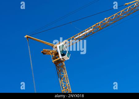 Frammento di una gru da costruzione con una cabina bianca contro il cielo blu. Foto Stock