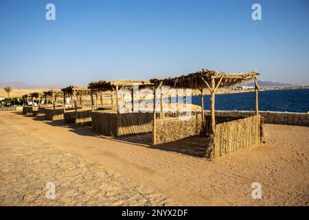 capanne vuote di paglia accanto al mare blu scuro Foto Stock