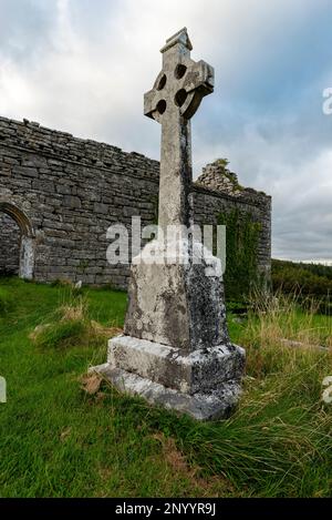 Enorme lapide a croce celtica che sorge di fronte alle rovine della Chiesa di Carran, il Parco Nazionale di Burren, Contea di Clare, Irlanda Foto Stock