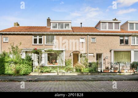 Amsterdam, Paesi Bassi - 10 aprile, 2021: Una casa nel mezzo di una zona urbana con un sacco di piante e fiori sul cortile, c'è un cielo blu Foto Stock