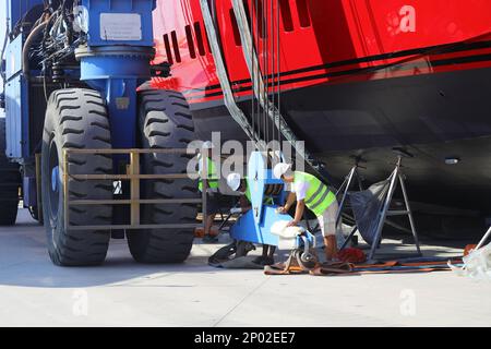 Didim, Aydin, Turchia. 20 giugno 2022: L'enorme ruota della gru che porta il Mega yacht è mantenuto a terra e i tecnici lavoratori ne lavoro Foto Stock