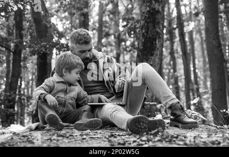 Carino ragazzino con suo padre durante una passeggiata nella foresta. Padre che gioca con piccolo figlio in un pic-nic nel parco nei primi giorni di autunno. Insegnamento genitore Foto Stock