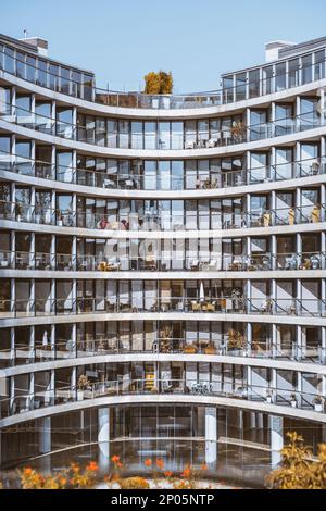 Uno scatto verticale di una facciata moderna di un edificio coperto da vetro trasuda prosperità e la sequenza di balconi con ringhiere senza cuciture crea un intri Foto Stock