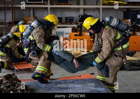 STATI UNITI Wesley Thompkins (a sinistra) e Shilo Burkhart, specialisti di salvataggio e antincendio (ARFF) assegnati a Marine Wing Support Squadron (MWSS) 171, Marine Aircraft Group (MAG) 12, trasportano un incidente simulato durante un addestramento di risposta di emergenza a MCAS Iwakuni, Giappone, 10 febbraio 2023. Questo corso di formazione è un requisito annuale per ARFF Marines in cui il personale di Iwakuni City Fire and Emergency Services coopera per migliorare la prontezza e l'efficienza nel rispondere a incidenti di massa sulla base in preparazione di potenziali scenari reali. Foto Stock