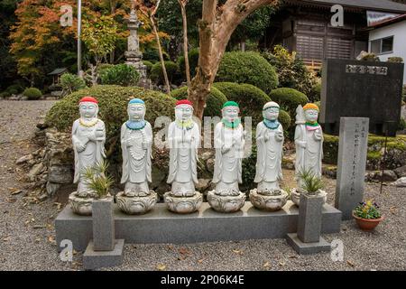 Statue di Gizoo, patroni di viaggiatori e bambini, indossando cappelli e bibs a maglia (kasa) al tempio di Jingui , Kamiyama, Giappone Foto Stock