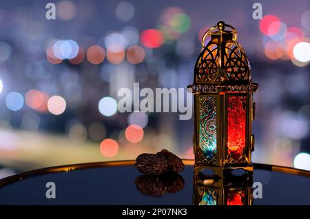 Lanterna e datteri frutta con cielo notturno e sfondo di luce bokeh della città per la festa musulmana del mese santo di Ramadan Kareem. Foto Stock