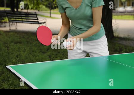 Giovane donna che gioca a ping pong nel parco, primo piano Foto Stock