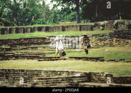 Agricoltori che camminano attraverso le rovine del Palazzo Surosowan, un patrimonio culturale del periodo Sultanato Banten situato in un'area chiamata Banten lama (Old Banten) a Serang, Banten, Indonesia, in questa foto scattata nel 2004. Una ricerca sul campo condotta recentemente da Nurikah e E. Rakhmat Jazuli (Facoltà di giurisprudenza, Sultan Ageng Tirtayasa University, Banten) ha rivelato che ci sono state molte violazioni contro il trattamento dei beni culturali nella zona. Foto Stock