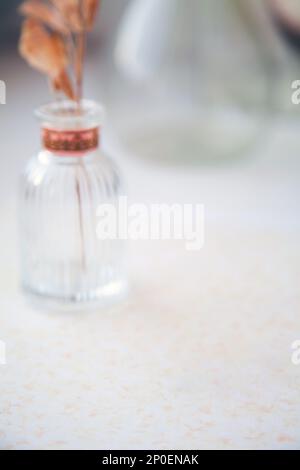 Le erbe essiccate in un vaso di vetro sfumato sfondo bianco. Sfocati articoli di vetro trasparente e autunno fiori asciutti sfondo Foto Stock